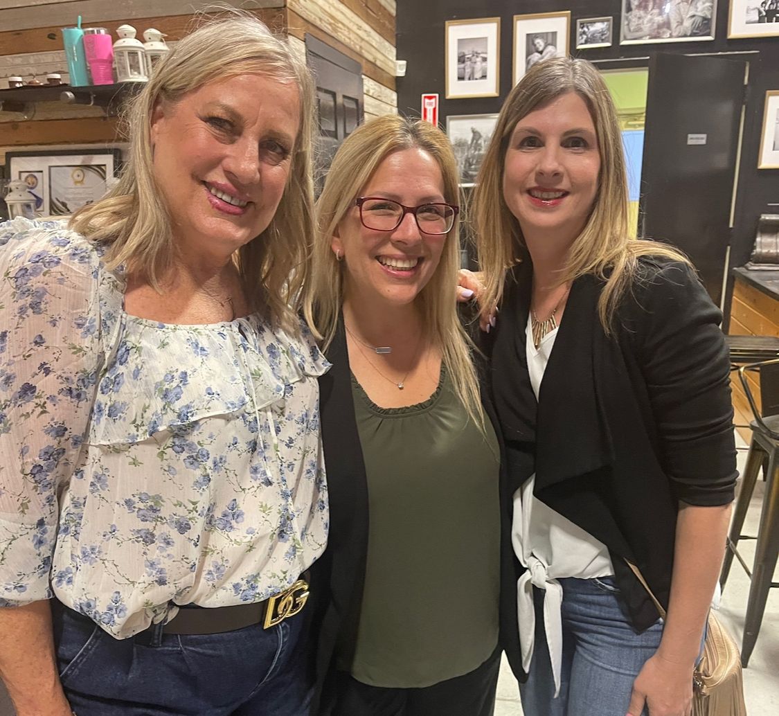 Linda Chevrier enjoying a Wine, Women, and Wealth event with her close friends Brandy and Robin, sharing smiles and laughter in a warm, supportive atmosphere.