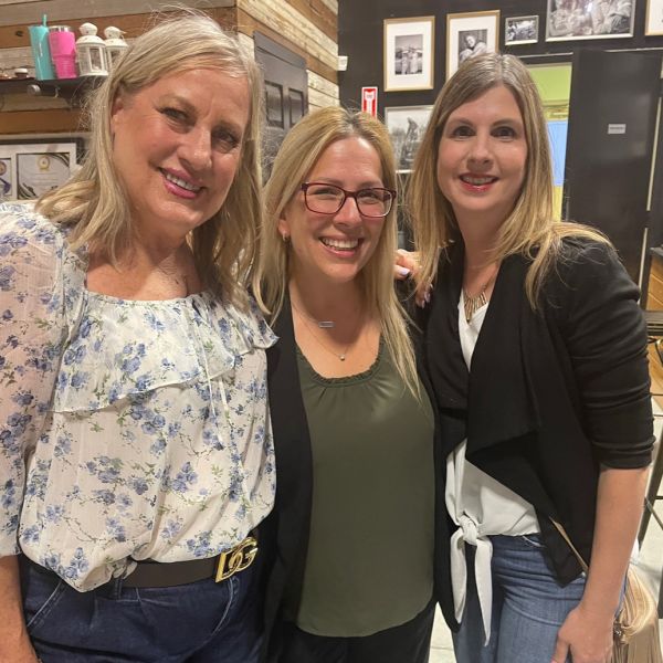 Linda Chevrier enjoying a Wine, Women, and Wealth event with her close friends Brandy and Robin, sharing smiles and laughter in a warm, supportive atmosphere.