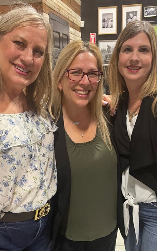 Linda Chevrier enjoying a Wine, Women, and Wealth event with her close friends Brandy and Robin, sharing smiles and laughter in a warm, supportive atmosphere.